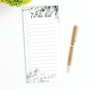 Peut inclure: Un bloc-notes blanc de liste de choses à faire avec un motif floral composé de feuilles vertes et de fleurs blanches. Le bloc-notes porte le titre "To do list" et comporte une ligne pour chaque élément de la liste.