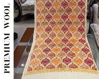 May include: A white shawl with a red, orange, and gold floral pattern. The shawl is made of wool and has a fringed edge.