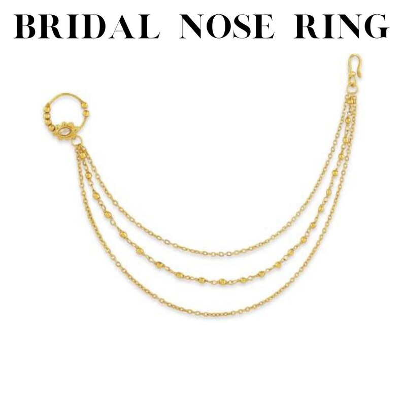 May include: Gold bridal nose ring with three chains and a small round ornament. The chains are adorned with small gold beads.
