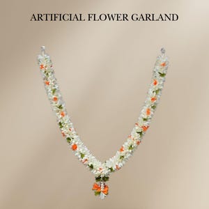Peut inclure: Guirlande de fleurs artificielles avec des fleurs blanches, oranges et vertes. La guirlande est en forme de V, avec un petit bouquet de fleurs en bas. Le texte "ARTIFICIAL FLOWER GARLAND" est en haut.