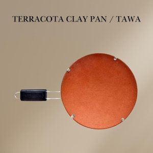 May include: Terracotta clay pan or tawa with a black handle. The pan is round and has a reddish-brown color.