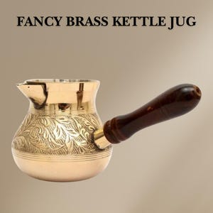 May include: A brass kettle with a wooden handle and an ornate floral design. The kettle is used for making Turkish coffee.