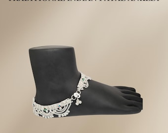 Könnte beinhalten: Silbernes Fußkettchen mit filigranen Designs und bunten Steinen. Das Fußkettchen befindet sich an einem schwarzen Mannequin-Fuß. "TRADITIONAL INDIAN PAYAL ANKLET" steht in schwarzer Schrift oben im Bild.