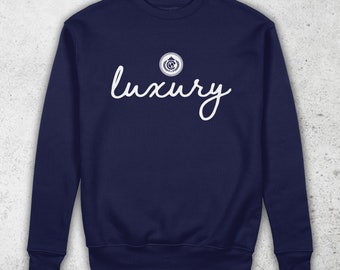 May include: Navy blue sweatshirt with a white cursive word "luxury" and a small white circular logo above it.