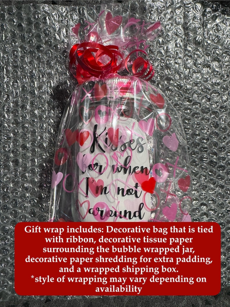 May include: A clear glass jar wrapped in cellophane with pink and red hearts and a red ribbon. The jar has the words "Kisses for when I'm not around" written on it. The jar is wrapped in bubble wrap.
