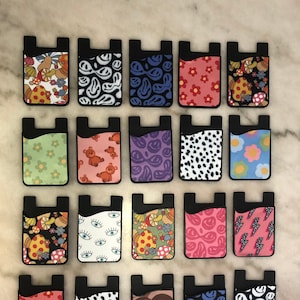 Peut inclure: Vingt supports de t&eacute;l&eacute;phone avec porte-cartes, aux motifs color&eacute;s et vari&eacute;s. Les motifs comprennent des champignons, des visages souriants, des yeux, des c&oelig;urs et des imprim&eacute;s animaliers.