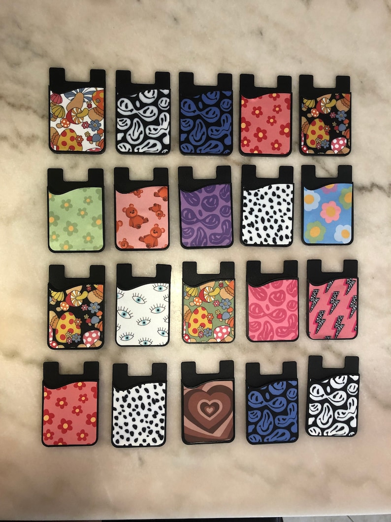 Peut inclure: Vingt supports de t&eacute;l&eacute;phone avec porte-cartes, aux motifs color&eacute;s et vari&eacute;s. Les motifs comprennent des champignons, des visages souriants, des yeux, des c&oelig;urs et des imprim&eacute;s animaliers.