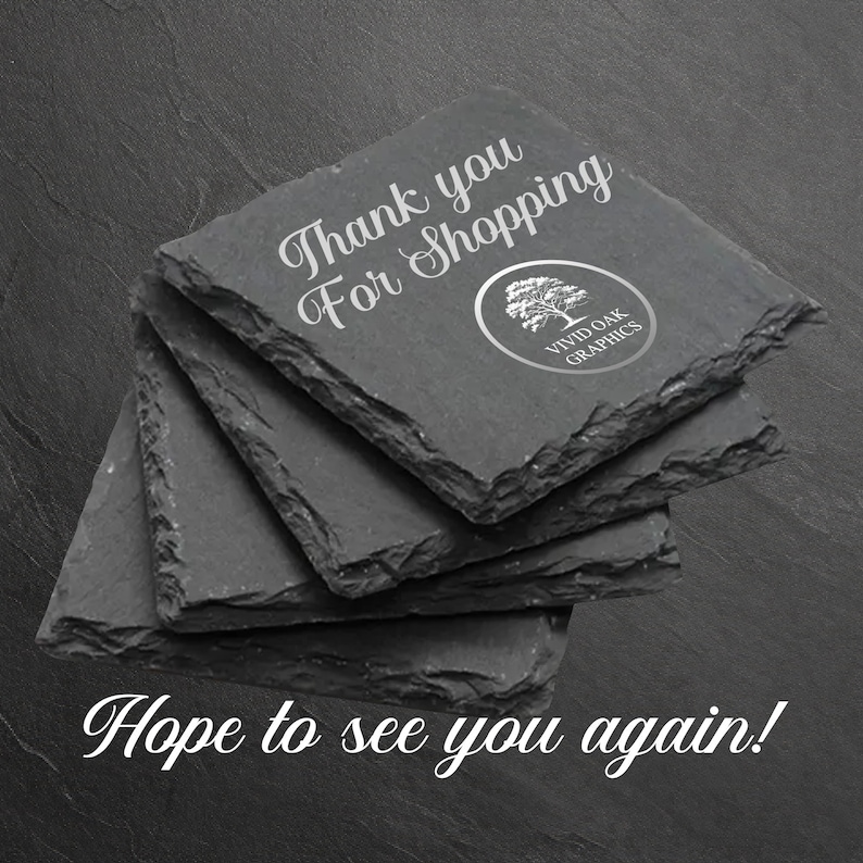 Puede incluir: Un conjunto de cuatro posavasos de pizarra negra con el texto "Gracias por comprar" y un logotipo que dice "Vivid Oak Graphics". El texto "&iexcl;Esperamos verte de nuevo!" est&aacute; escrito debajo de los posavasos.