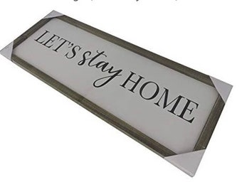 May include: A white wooden sign with a gray frame reads "Let's stay home".