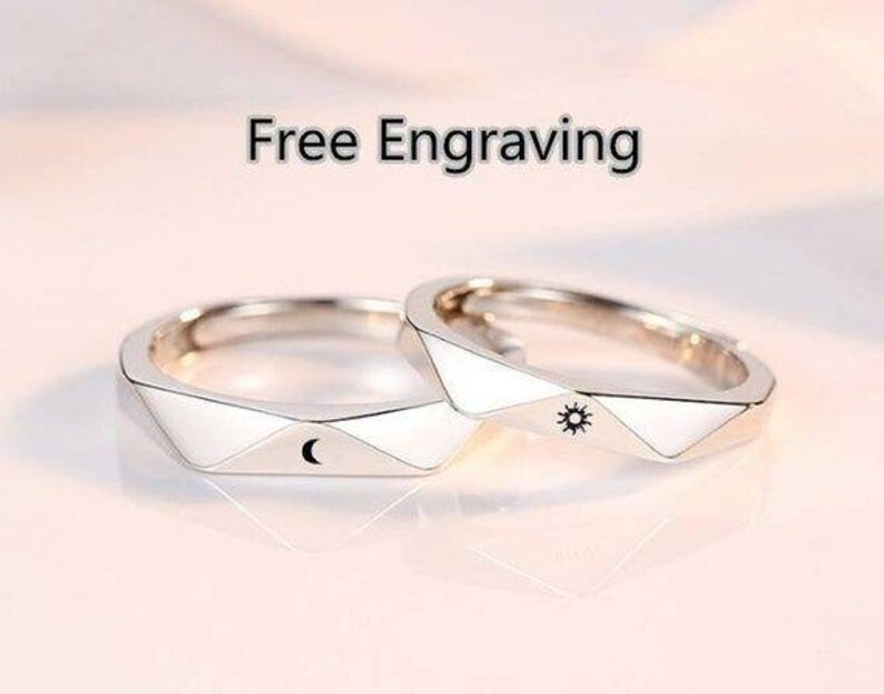 May include: Two silver rings with geometric designs. One ring features a crescent moon and the other features a sun.