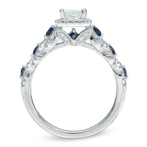 May include: A silver engagement ring with a square-cut center stone surrounded by smaller diamonds. The band is adorned with blue sapphires and smaller diamonds.