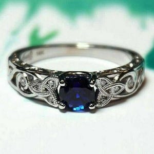 May include: A silver ring featuring a blue sapphire gemstone and intricate Celtic knot design. The ring is set with smaller diamonds around the sapphire.