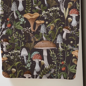May include: A fabric with a dark background featuring a watercolor pattern of various mushrooms, plants, and insects. The mushrooms are in shades of brown, red, and white, with green foliage and small red berries. The design is detailed and botanical.