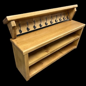 Puede incluir: Un banco de entrada de madera marr&oacute;n claro que cuenta con un estante superior con diez ganchos de metal negro y dos estantes de almacenamiento abiertos en la parte inferior. La unidad es de madera natural con veta visible y superficie lisa.