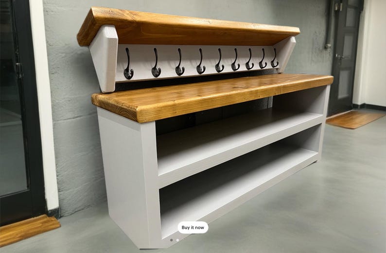 Puede incluir: Un mueble de recibidor con base gris claro, dos estantes abiertos y una secci&oacute;n superior a juego con tapa de madera natural. La parte superior incluye nueve ganchos de metal negro para colgar objetos, montados sobre un panel trasero gris claro.