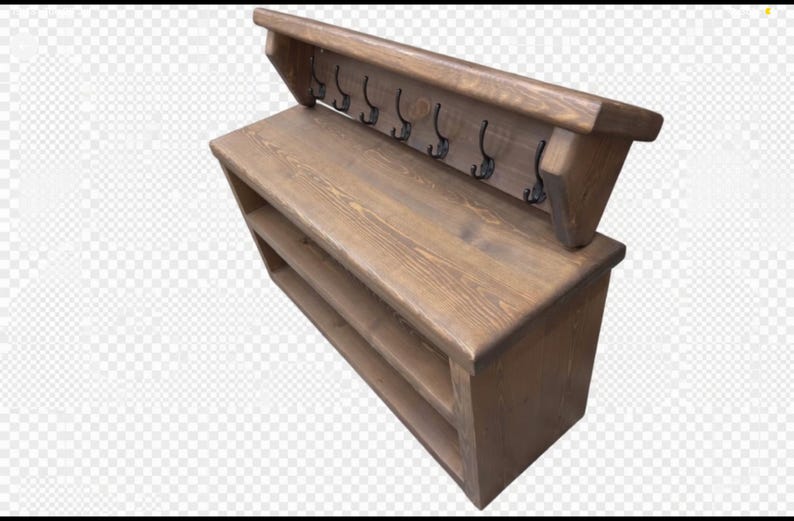 Puede incluir: Un banco de entrada de madera marr&oacute;n con una superficie superior plana, dos estantes de almacenamiento abiertos debajo y un panel trasero con seis ganchos de metal negro para colgar objetos. La unidad est&aacute; hecha de madera con veta visible.