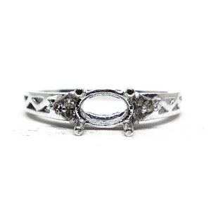 May include: A silver ring with an oval-shaped setting and two small diamonds on the band.