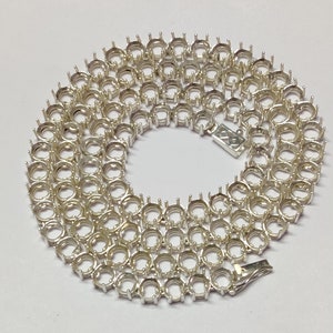 May include: A silver chain with round settings for gemstones. The chain is made of metal and has a clasp.