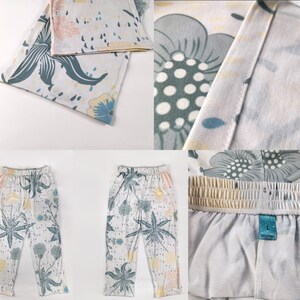 Op de afbeelding: Een witte broek met een bloemenprint in tinten blauw, groen en geel. De broek heeft een trekkoord in de tailleband en een ontspannen pasvorm.