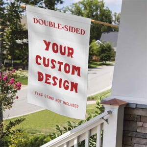 May include: A white, double-sided flag with red text that reads "DOUBLE-SIDED", "YOUR CUSTOM DESIGN", and "FLAG STAND NOT INCLUDED". The flag is hanging outside on a wooden pole.