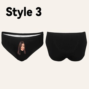 Op de afbeelding: Zwarte onderbroek met een witte tailleband. De voorkant van de onderbroek heeft een geprinte afbeelding van een vrouwen gezicht.