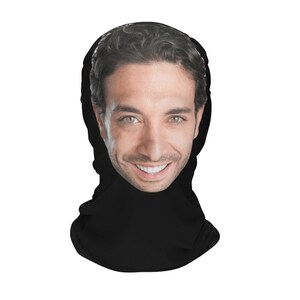 K&ouml;nnte beinhalten: Eine schwarze Gesichtsmaske mit einem darauf gedruckten Gesicht. Die Person l&auml;chelt und hat braunes Haar.