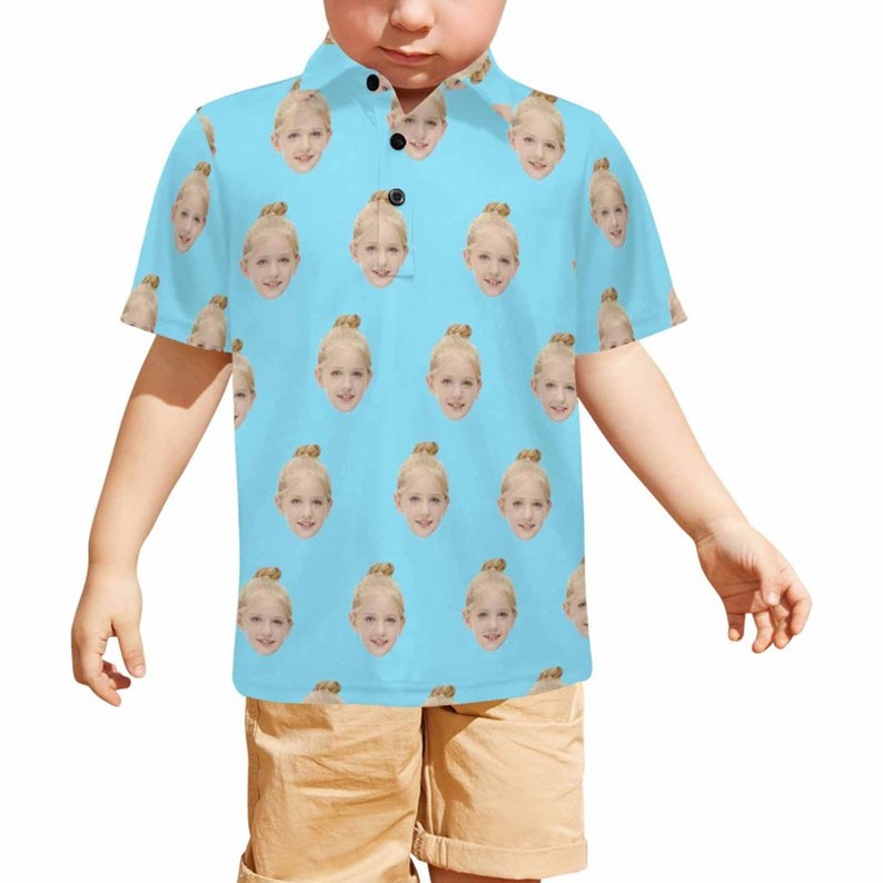 May include: A light blue short-sleeved polo shirt with a repeating pattern of a young girl's face.