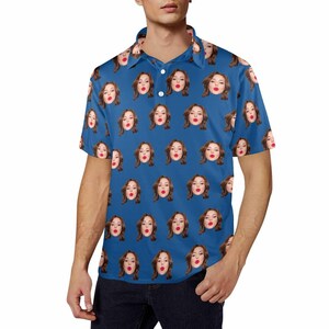May include: A blue short-sleeved polo shirt with a repeating pattern of a woman's face. The woman is wearing red lipstick and has her lips slightly parted.