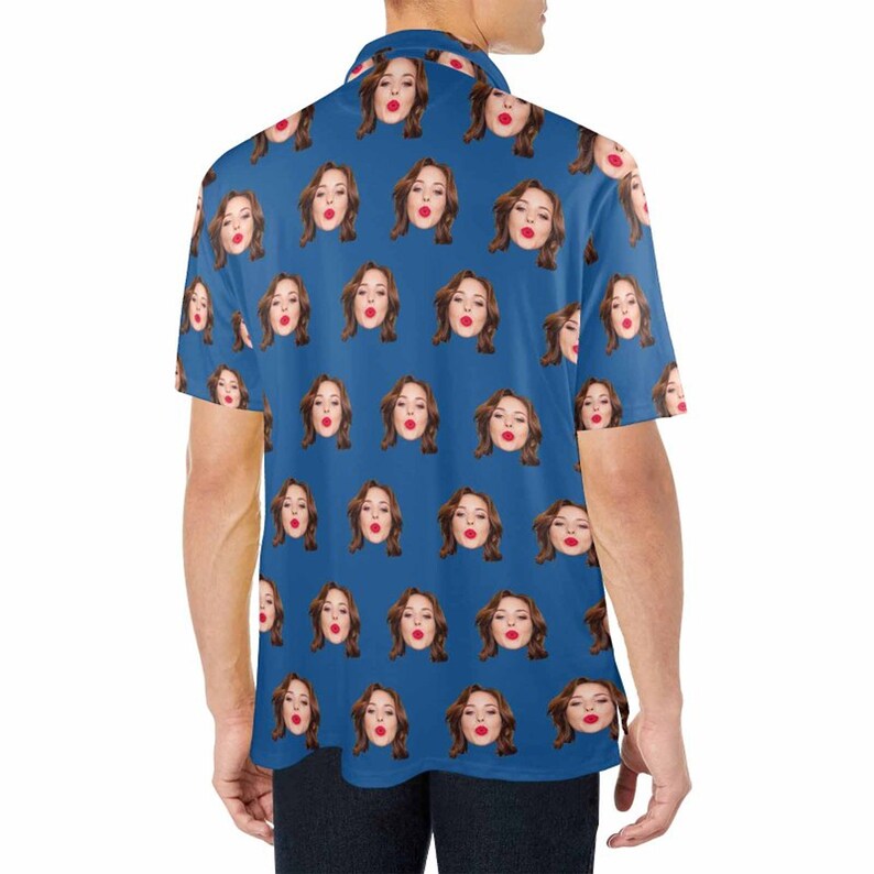 May include: A blue short-sleeved shirt with a repeating pattern of a woman's face. The woman is wearing red lipstick and has brown hair.