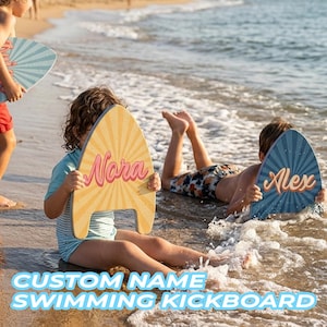 May include: Two surfboard-shaped swimming kickboards with sunburst patterns. One yellow board features the name Nora in pink script, and one blue board features the name Alex in orange script. Both boards have a cutout at the bottom edge.