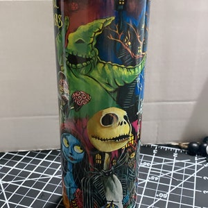 K&ouml;nnte beinhalten: Ein Edelstahlbecher mit Figuren aus "The Nightmare Before Christmas". Das Design umfasst Jack Skellington, Sally, Oogie Boogie und andere Charaktere vor einem dunklen, gruseligen Hintergrund. Der Becher hat einen transparenten Deckel.