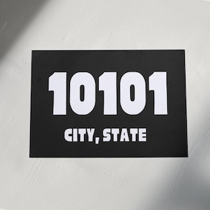 Può includere: Un cartello bianco e nero con il numero 10101 e il testo "CITY, STATE" in bianco.