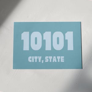 Può includere: Un cartello rettangolare blu chiaro con il numero 10101 stampato in bianco e il testo "CITY, STATE" stampato sotto il numero.