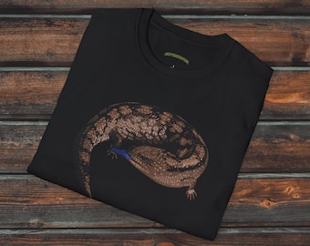 Op de afbeelding: Zwart T-shirt met een grafische print van een blauwe tongskink die op een zwarte achtergrond is opgerold. De tekst "Creepy Crawly Apparel" is in wit bovenaan de afbeelding gedrukt.