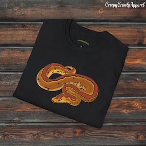 May include: Black t-shirt with a graphic of a curled up orange and brown snake. The snake has a pattern of brown spots and a red stripe.