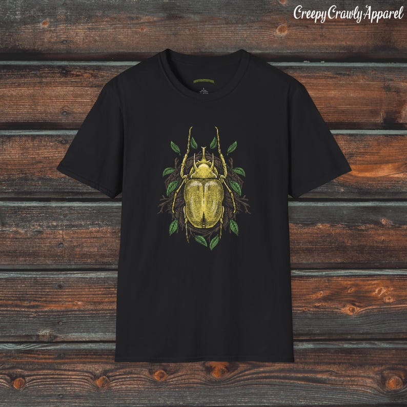 May include: Black t-shirt with a yellow beetle illustration surrounded by green leaves. The beetle has a detailed design and is set against a dark background. The text "Creepy Crawly Apparel" is visible in the top right corner.