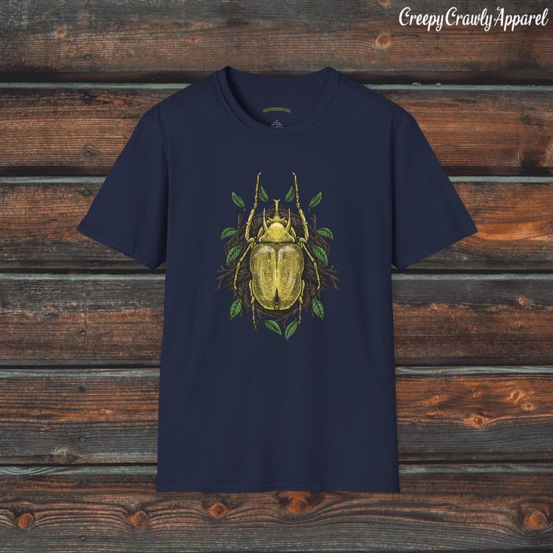 May include: Navy blue t-shirt with a yellow beetle illustration surrounded by green leaves. The beetle has a detailed design and is set against a dark background.