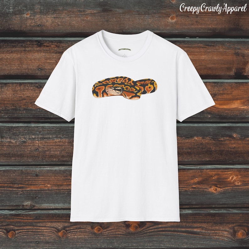 May include: White t-shirt with a graphic of a curled up snake with orange, brown, and black markings.
