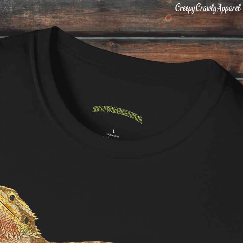 Op de afbeelding: Zwart T-shirt met een afbeelding van een baardagamenkop. Het shirt heeft een label met de tekst "CreepyCrawlyApparel" en "100% Katoen".