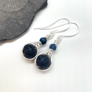 Peut inclure: Boucles d'oreilles pendantes en argent avec des perles de lave noire et des accents de pierres précieuses bleues.
