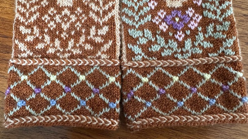 May include: Close-up of two sections of a knitted textile. The brown fabric features intricate patterns in cream, light blue, purple, and green. The design includes geometric shapes and floral motifs, with a decorative border.