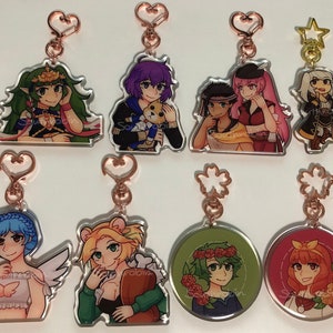 Peut inclure: Ensemble de dix porte-clés de personnages d'anime colorés avec des anneaux en métal rose gold. Les porte-clés présentent des personnages avec des couleurs de cheveux, des tenues et des accessoires différents.