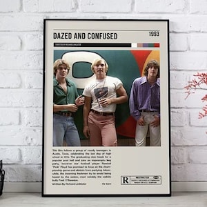 May include: A framed movie poster for "Dazed and Confused" from 1993. The poster features a photo of three young men in 1970s attire. The poster has the movie title, year, and rating. The poster is displayed on a white brick wall.