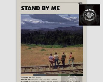 May include: A movie poster for "Stand By Me" featuring four boys standing on railroad tracks, with a scenic backdrop of a field, trees, and a cloudy sky. The poster includes the movie title, credits, and a small logo in the upper right corner.