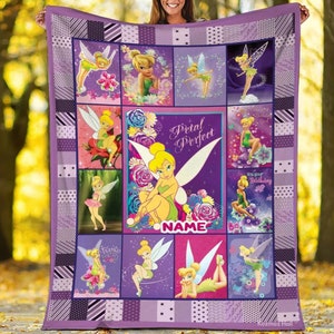 K&ouml;nnte beinhalten: Eine lila-wei&szlig;e Steppdecke mit Bildern von Tinkerbell. Die Steppdecke hat ein Patchwork-Design mit verschiedenen Bildern der Fee, zusammen mit den Worten "Petal Perfect" und einem Platz f&uuml;r einen Namen. Die Decke wird von einer Person gehalten.