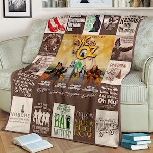 Peut inclure: Une couverture marron et beige avec des images du "Magicien d'Oz". La couverture affiche des personnages, des citations et le titre du film. La couverture est drapée sur un canapé beige.
