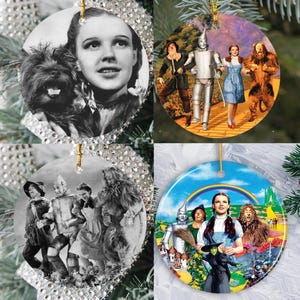 May include: Set of four round Christmas ornaments featuring scenes and characters from the classic film "The Wizard of Oz." The ornaments include images of Dorothy, Toto, the Tin Man, Scarecrow, Lion, and the Wicked Witch.