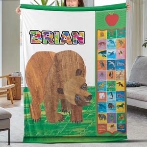 Peut inclure: Une grande couverture colorée avec une illustration d'ours brun et le nom "BRIAN" en lettres arc-en-ciel. Elle comprend également un tableau de l'alphabet avec des illustrations d'animaux et une pomme rouge.