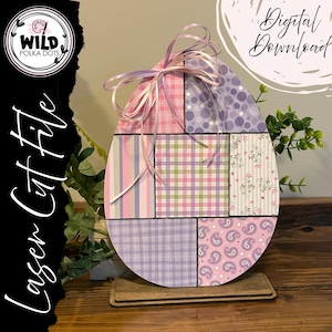 Peut inclure: Un fichier de découpe laser en forme d'œuf de Pâques en bois avec un motif patchwork. Le design comprend divers motifs en rose, violet et vert, avec un nœud en ruban en haut. Le texte "Digital Download" est visible. Le logo Wild Polka Dots est également visible.