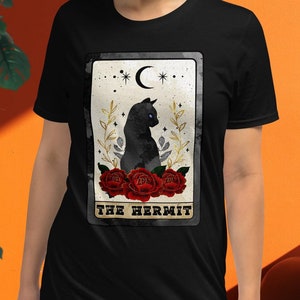 May include: Black t-shirt with a tarot card design featuring a black cat sitting on red roses with the text "The Hermit".